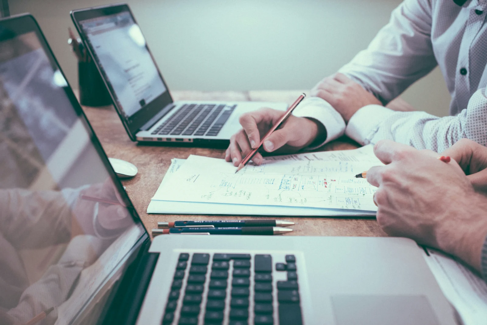 Profissionais de contabilidade reunidos em um escritório analisando relatórios e dados em um notebook.